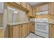 This kitchen includes an efficient layout with clean white appliances and ample wood cabinets for storage at 1737 Pine Ridge W Way # B-1, Palm Harbor, FL 34684