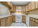 This clean, well-lit kitchen features wood cabinets, bright appliances, and a tile floor at 1737 Pine Ridge W Way # B-1, Palm Harbor, FL 34684