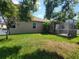 Well-maintained backyard featuring lush green grass, a screen porch, and mature trees at 1803 Roseroot Ct, Trinity, FL 34655