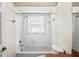 Bright white bathroom features a shower over tub with window and neutral decor at 303 Rochester St, Spring Hill, FL 34609