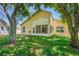 Back exterior of home with large windows, door and beautiful landscaping at 303 Rochester St, Spring Hill, FL 34609