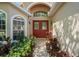 Inviting entryway featuring a double door entrance, arched windows, and lush landscaping at 303 Rochester St, Spring Hill, FL 34609