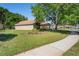 Well-maintained home on a corner lot, featuring lush landscaping, mature trees, and a welcoming curb appeal at 303 Rochester St, Spring Hill, FL 34609