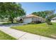 Charming single-story home with a well-manicured lawn, mature trees, and a welcoming two-car garage at 303 Rochester St, Spring Hill, FL 34609