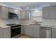 Well-lit kitchen featuring stainless steel appliances, gray cabinets and tiled backsplash at 4964 Cedarbrook Ln, Hernando Beach, FL 34607
