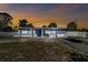 Charming single Gathering home, front view with driveway and sunset, featuring mature trees and inviting curb appeal at 6250 Vermont Ave, New Port Richey, FL 34653