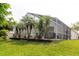 An ample grass lawn extends beyond the house to a screened-in pool and patio area at 7239 Sharpsburg Blvd, New Port Richey, FL 34653