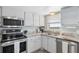 Well-lit kitchen with stainless steel appliances, white cabinetry and granite countertops at 9 Forbes Pl # 512, Dunedin, FL 34698