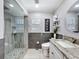 Renovated bathroom showcasing tiled shower, gray accent wall, and a round mirror at 10136 Highcrest Ln, New Port Richey, FL 34654