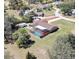 Aerial view of home with a screened-in pool, well-maintained lawn, and mature trees at 10200 Swanson Ct, Spring Hill, FL 34608