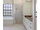 Bright bathroom featuring a large bathtub under a window and a glass-enclosed shower at 1038 Greenturf Rd, Spring Hill, FL 34608