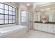 Bright bathroom featuring a large window, tub, glass shower, granite counters, and neutral colors at 1038 Greenturf Rd, Spring Hill, FL 34608