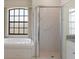 Well-lit bathroom featuring a glass shower, tub under a window, and neutral tile at 1038 Greenturf Rd, Spring Hill, FL 34608