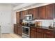 Kitchen with stainless steel appliances, dark wood cabinets, granite countertops, and white tile backsplash at 1038 Greenturf Rd, Spring Hill, FL 34608