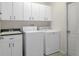 Laundry room features white cabinets, sink, and modern white washer and dryer units at 1038 Greenturf Rd, Spring Hill, FL 34608