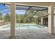 Backyard pool features screened-in lanai enclosure with brick pavers and a serene view of trees at 1038 Greenturf Rd, Spring Hill, FL 34608