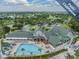 Aerial view showcasing the pool, clubhouse, and surrounding community amenities, set against a backdrop of mature trees at 11428 Hidden Cove Ct, Trinity, FL 34655