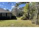 View of home's backyard with green lawn area and surrounding trees at 12342 Quigley Ave, Weeki Wachee, FL 34614