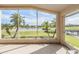 Screened lanai with serene waterfront view featuring palm trees and clear skies at 1809 Westerham Loop, Trinity, FL 34655