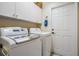 Bright laundry room featuring a washer, dryer, and overhead cabinets at 1809 Westerham Loop, Trinity, FL 34655