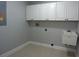 Bright laundry room with white cabinets, tile floors, and a utility sink offers a clean and functional space at 19109 Beckett Dr, Odessa, FL 33556