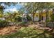 Beautifully landscaped backyard features charming playhouse nestled among mature trees and natural elements at 200 Grand Blvd, Tarpon Springs, FL 34689