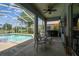 Covered patio area features outdoor seating, a ceiling fan, and views of a screened-in pool and lake at 22129 Yachtclub Ter, Land O Lakes, FL 34639