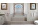 Bright bathroom features a soaking tub under a glass block window with decorative curtains and tiled surround at 2375 Fairskies Dr, Spring Hill, FL 34606