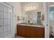Bathroom with dual sinks, granite countertops, wood cabinets, and bright lighting with a separate commode room at 2375 Fairskies Dr, Spring Hill, FL 34606