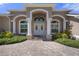 Inviting front entrance featuring elegant double doors, columns, and lush landscaping at 2375 Fairskies Dr, Spring Hill, FL 34606