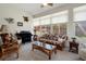 Bright living room featuring rattan furniture, a piano, and large windows with garden views at 2375 Fairskies Dr, Spring Hill, FL 34606
