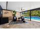Relax in this covered outdoor space with a view of the sparkling pool, complete with comfortable seating and tile flooring at 319 S Glen Arven Ave, Temple Terrace, FL 33617