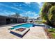 Beautiful pool area with a spa, sun shelf, fire pit and travertine tile, set amidst tropical landscaping and a white pergola at 319 S Glen Arven Ave, Temple Terrace, FL 33617