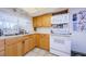 A full kitchen with wood cabinets, white appliances, and a window above the sink at 4107 Glissade Dr, New Port Richey, FL 34652