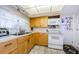 A full kitchen with wood cabinets, white appliances, and a window above the sink at 4107 Glissade Dr, New Port Richey, FL 34652
