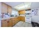Kitchen with white appliances, tile floor, wood cabinets, and a bright, paneled ceiling light at 4107 Glissade Dr, New Port Richey, FL 34652