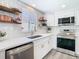 Bright kitchen features stainless steel appliances, white cabinets, tile backsplash, and open wood shelving at 4936 Dory Dr, New Port Richey, FL 34652