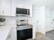 Modern kitchen with stainless steel appliances, white cabinets, quartz countertop, and a sleek microwave and range at 4936 Dory Dr, New Port Richey, FL 34652