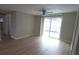 Bright living room featuring wood floors, neutral walls, ceiling fan, and sliding glass doors to the outdoor pool at 7024 Coral Reef Dr, Port Richey, FL 34668