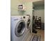 Bright laundry room with front load washer and dryer and overhead storage shelves at 8405 Blue Rock Dr, New Port Richey, FL 34653