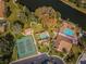 Aerial view of community amenities: tennis courts, pool, clubhouse, and serene pond with landscaped grounds at 9336 Cape Charles Ave, New Port Richey, FL 34655