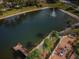 Aerial view showcases a tranquil lake with a fountain, a dock, and a brick patio with seating at 9336 Cape Charles Ave, New Port Richey, FL 34655