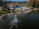 Aerial view of a community pool, clubhouse, and lake with fountain, showcasing amenities and waterfront views at 9336 Cape Charles Ave, New Port Richey, FL 34655