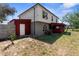 View of the home's back exterior featuring a red shed and access to the back yard at 10399 Elgin Blvd, Spring Hill, FL 34608