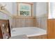 Bright bathroom with a soaking tub, wood trim, and a view from the window at 10399 Elgin Blvd, Spring Hill, FL 34608