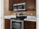 Close-up of a kitchen featuring stainless steel appliances, including a range and microwave, with tile countertops at 10399 Elgin Blvd, Spring Hill, FL 34608