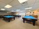 Spacious billiard room equipped with three Diamond pool tables, comfortable seating, and overhead lighting at 10635 Timber Ln, Port Richey, FL 34668