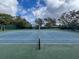 Well-maintained tennis court surrounded by trees, offering a great space for recreation and exercise at 10635 Timber Ln, Port Richey, FL 34668