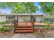 Backyard view showcasing a deck with seating, accessible by brick steps, set among mature trees at 11326 Minnieola Dr, New Port Richey, FL 34654