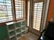 Bedroom with shuttered windows and door to balcony with views of waterfront and bookshelf at 121 Augusta Ave, Palm Harbor, FL 34683